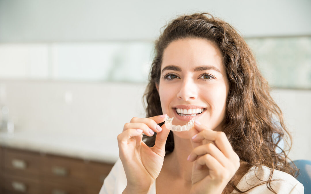 Woman with perfect smile holding invisalign